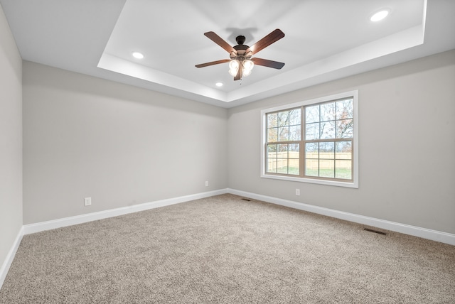 spare room featuring carpet, ceiling fan, and a tray ceiling