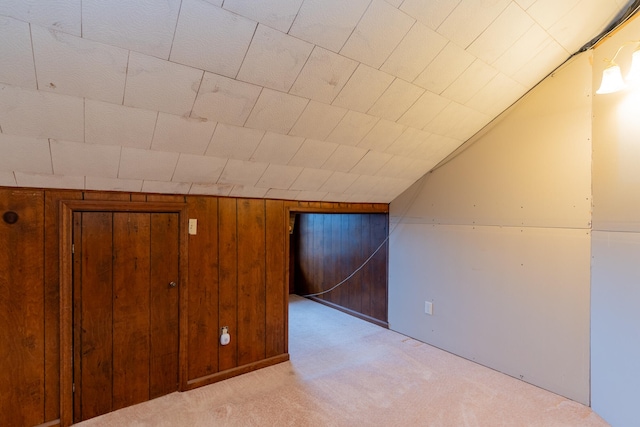 bonus room featuring lofted ceiling, light carpet, and wood walls