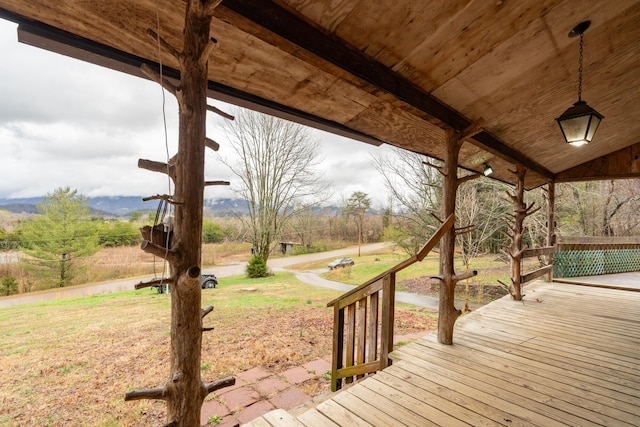 wooden terrace featuring a mountain view and a lawn