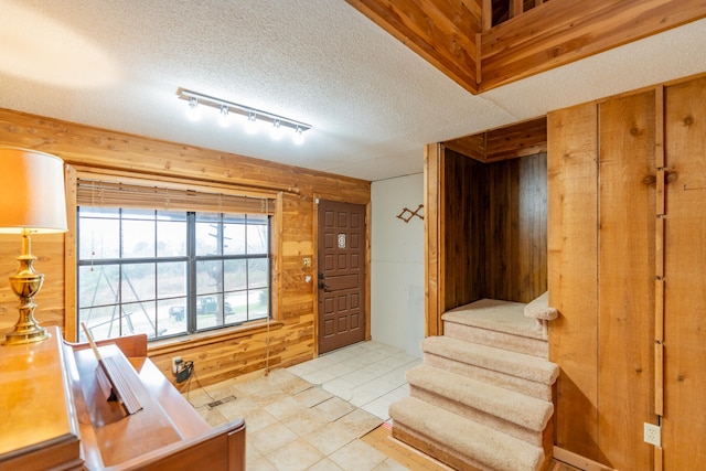 interior space with a textured ceiling and wooden walls