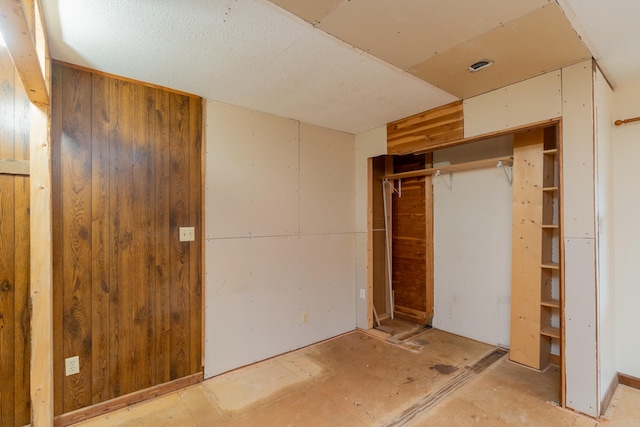 unfurnished bedroom featuring a closet and wooden walls