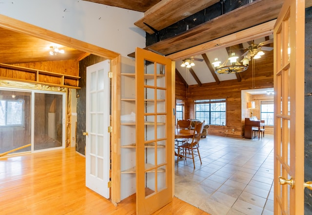 unfurnished dining area featuring vaulted ceiling with beams, french doors, light hardwood / wood-style floors, and ceiling fan