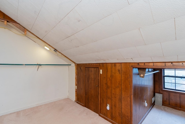 additional living space with wood walls, lofted ceiling, and light colored carpet