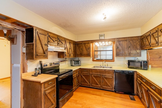 kitchen featuring sink, black appliances, a textured ceiling, and light hardwood / wood-style floors