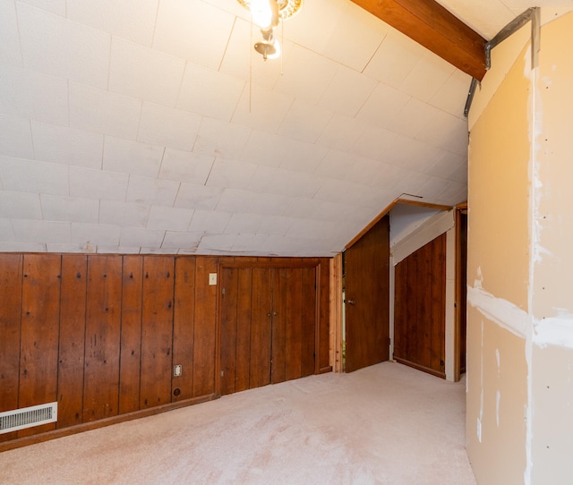 bonus room featuring light carpet, wooden walls, and vaulted ceiling with beams