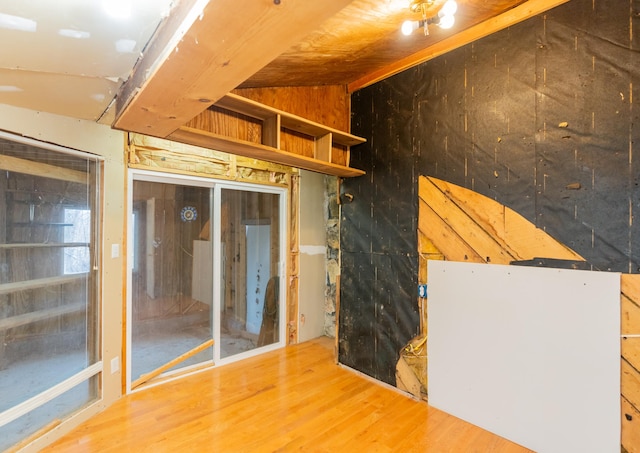 interior space featuring lofted ceiling, wooden walls, and hardwood / wood-style flooring