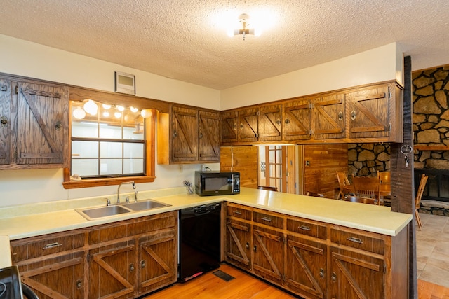 kitchen featuring light wood-type flooring, black appliances, sink, and kitchen peninsula