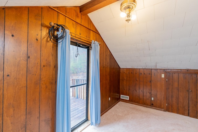 additional living space with light colored carpet, wood walls, and lofted ceiling with beams