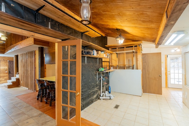 basement featuring light tile patterned flooring, wooden ceiling, and wood walls