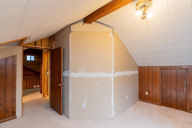 bonus room with wooden walls, vaulted ceiling with beams, and light colored carpet