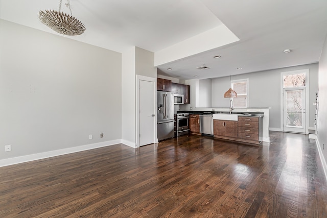 kitchen with high quality appliances, hanging light fixtures, sink, and dark hardwood / wood-style flooring