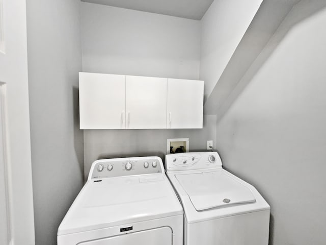 clothes washing area with washer hookup, cabinets, and washing machine and clothes dryer