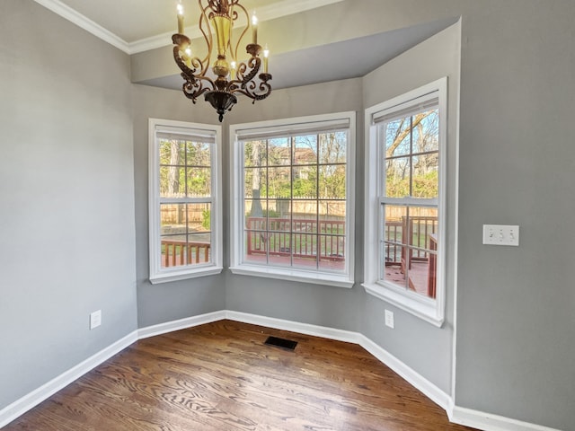 unfurnished room featuring an inviting chandelier, dark wood-type flooring, and ornamental molding