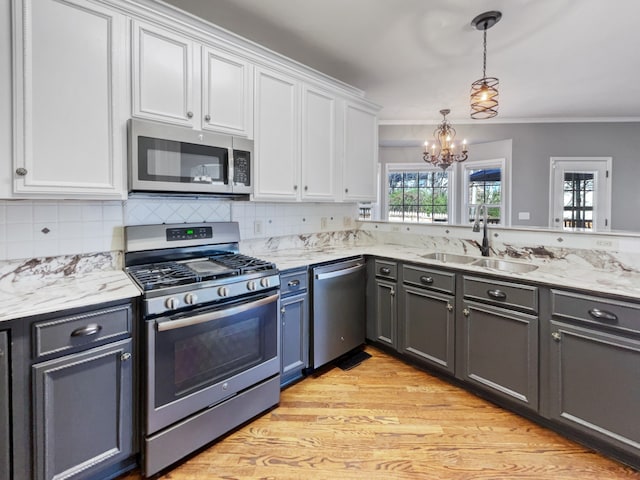 kitchen featuring an inviting chandelier, white cabinets, appliances with stainless steel finishes, and light hardwood / wood-style flooring