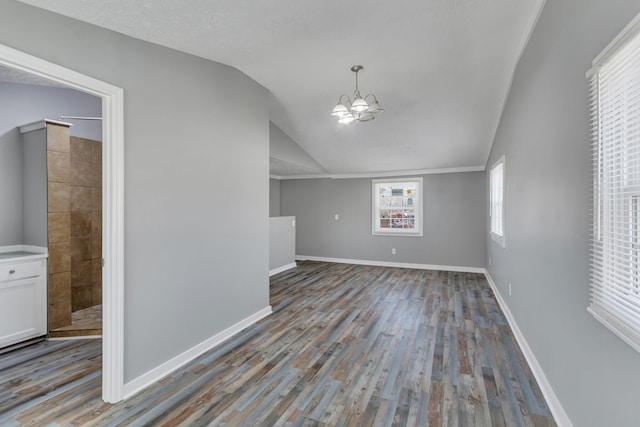 spare room featuring a notable chandelier, lofted ceiling, a textured ceiling, and wood-type flooring