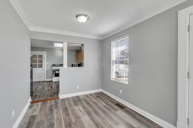 empty room with a textured ceiling, hardwood / wood-style flooring, and crown molding