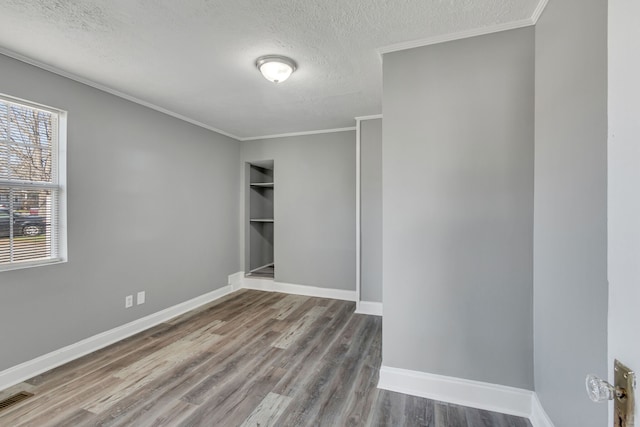 unfurnished room featuring hardwood / wood-style floors, a textured ceiling, plenty of natural light, and ornamental molding