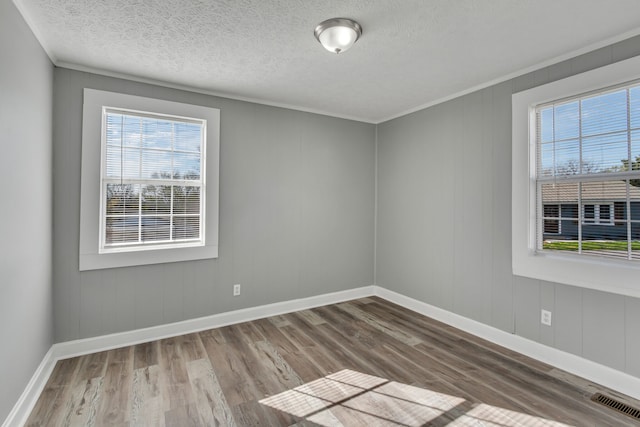 spare room with hardwood / wood-style floors, a textured ceiling, and ornamental molding