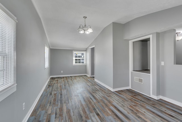 unfurnished room with a notable chandelier, lofted ceiling, a textured ceiling, and dark hardwood / wood-style floors