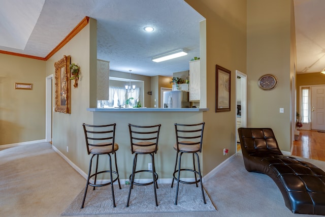 kitchen with stainless steel refrigerator with ice dispenser, light colored carpet, a kitchen breakfast bar, and a wealth of natural light