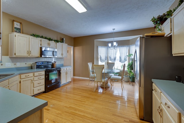 kitchen featuring appliances with stainless steel finishes, pendant lighting, tasteful backsplash, light hardwood / wood-style floors, and a chandelier