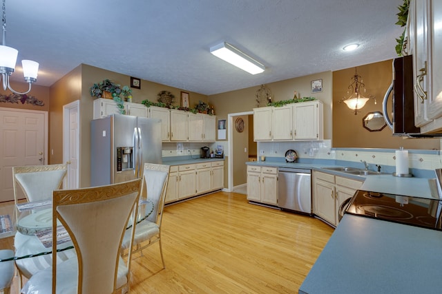 kitchen featuring an inviting chandelier, light hardwood / wood-style floors, stainless steel appliances, tasteful backsplash, and decorative light fixtures