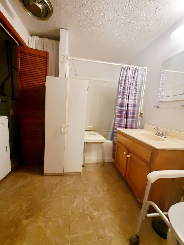 bathroom featuring washer / clothes dryer, vanity, tile patterned floors, and a textured ceiling