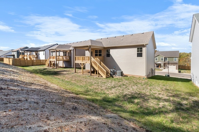 rear view of house with a lawn, a wooden deck, and central air condition unit