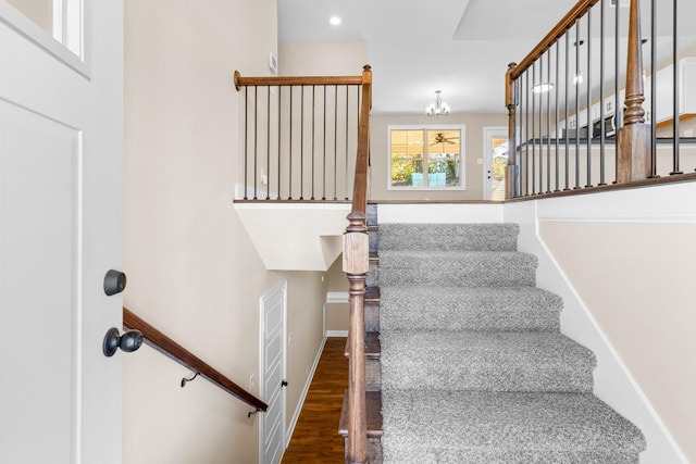 stairs featuring hardwood / wood-style floors and a notable chandelier