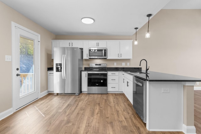 kitchen featuring white cabinets, sink, hanging light fixtures, kitchen peninsula, and stainless steel appliances