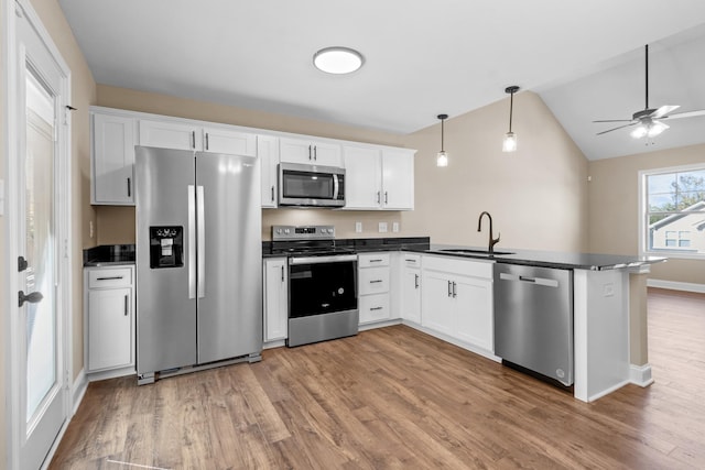 kitchen with appliances with stainless steel finishes, white cabinetry, lofted ceiling, and sink