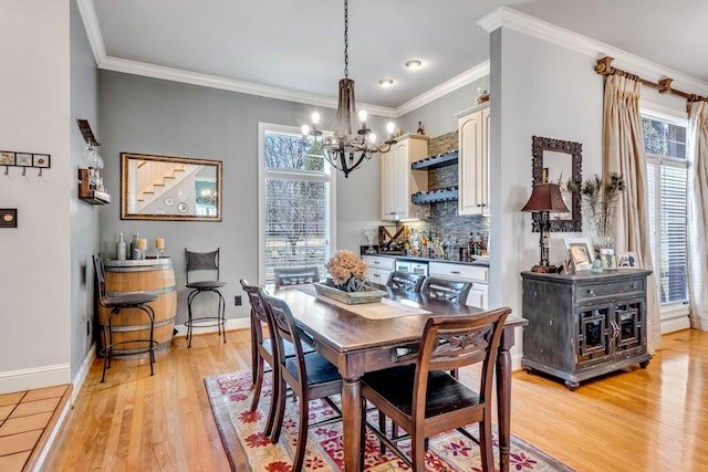 dining space with a healthy amount of sunlight, light wood-type flooring, ornamental molding, and a chandelier