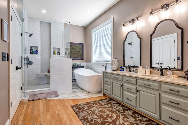 bathroom featuring wood-type flooring, vanity, shower with separate bathtub, and tile walls