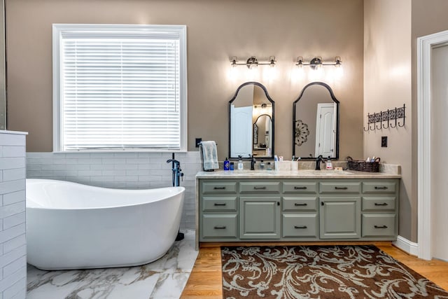 bathroom with vanity, wood-type flooring, and a bath