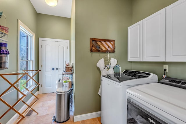 clothes washing area with washer and dryer, light tile patterned flooring, and cabinets