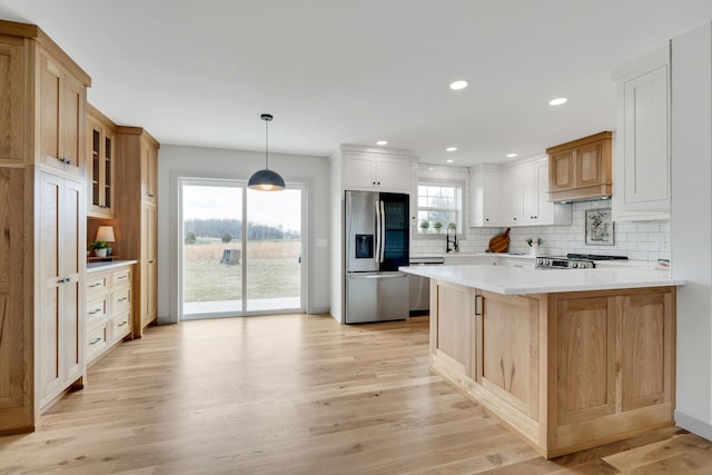 kitchen with stainless steel appliances, light wood-type flooring, hanging light fixtures, and white cabinets