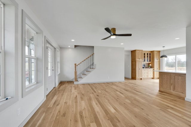 unfurnished living room featuring ceiling fan and light wood-type flooring