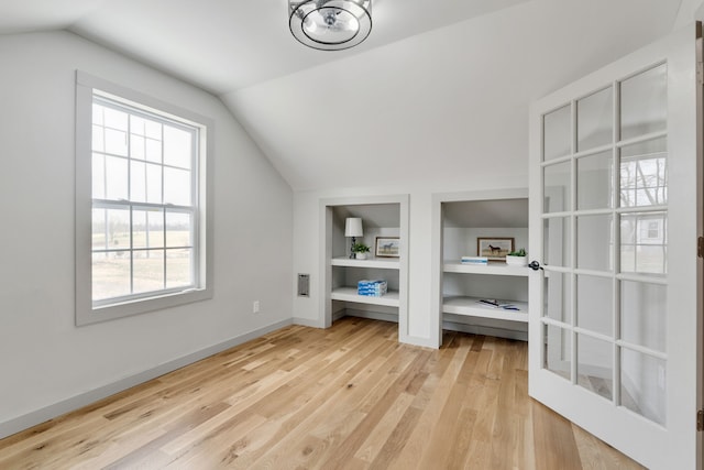 bonus room featuring lofted ceiling, built in features, and light wood-type flooring