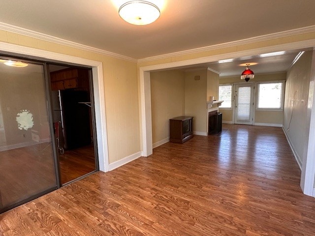 unfurnished living room featuring dark wood-type flooring and crown molding