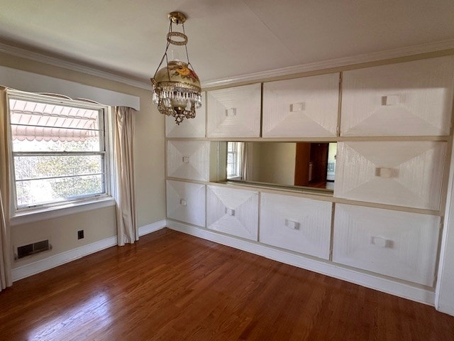 spare room featuring an inviting chandelier, crown molding, and dark hardwood / wood-style floors