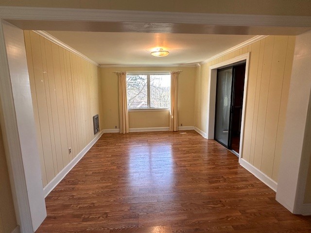 empty room featuring crown molding and dark wood-type flooring