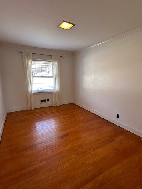 spare room with light wood-type flooring and ornamental molding