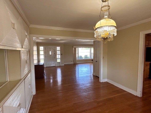 empty room featuring a notable chandelier, ornamental molding, and dark wood-type flooring