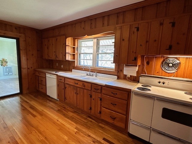 kitchen with white appliances, light hardwood / wood-style floors, wooden walls, and sink