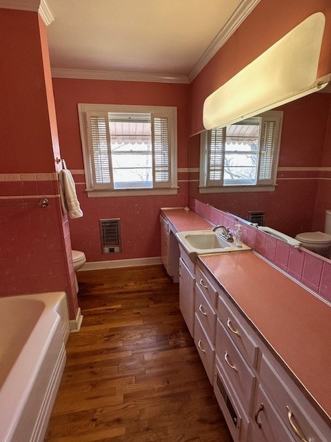 bathroom featuring toilet, a washtub, vanity with extensive cabinet space, ornamental molding, and hardwood / wood-style floors