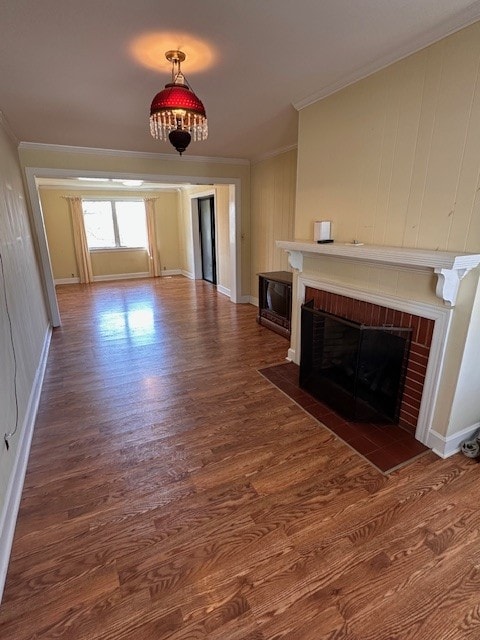 unfurnished living room with crown molding, a brick fireplace, and dark wood-type flooring