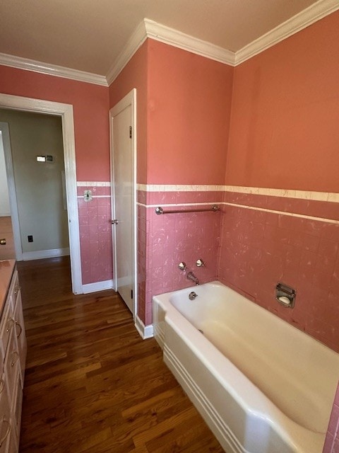 bathroom featuring crown molding, hardwood / wood-style floors, a washtub, and vanity