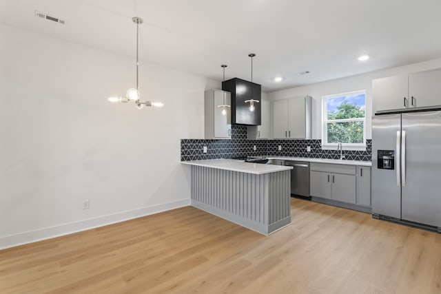 kitchen with an inviting chandelier, kitchen peninsula, light hardwood / wood-style flooring, and stainless steel appliances