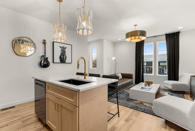 kitchen with a wealth of natural light, decorative light fixtures, black dishwasher, sink, and a center island with sink