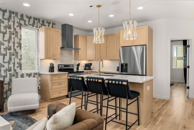 kitchen featuring wall chimney range hood, light hardwood / wood-style floors, sink, appliances with stainless steel finishes, and light brown cabinetry